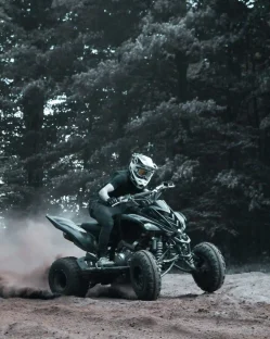 A rider speeding on an ATV on a dirt path, leaving a trail of dust behind.