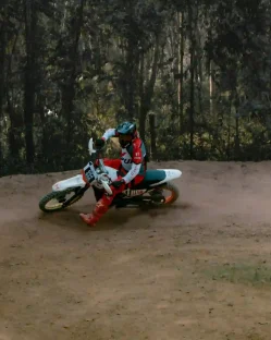 A person riding a dirt bike on a sandy dirt trail, kicking up dust.